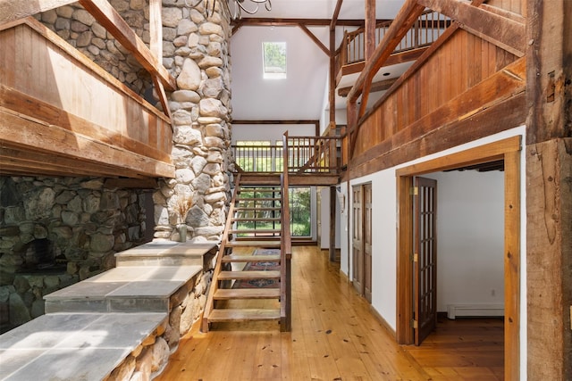880 W Mill Rd, Mattituck, NY 11952 - stairway featuring a towering ceiling, wood-type flooring, and a baseboard radiator