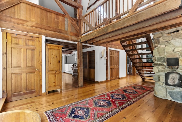 880 W Mill Rd, Mattituck, NY 11952 - unfurnished living room featuring hardwood / wood-style flooring, stairs, a high ceiling, and a fireplace