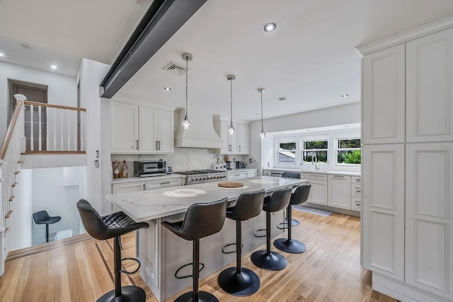 5 Pickett Ct, Malverne, NY 11565 - kitchen featuring white cabinets, a kitchen breakfast bar, custom range hood, backsplash, and recessed lighting