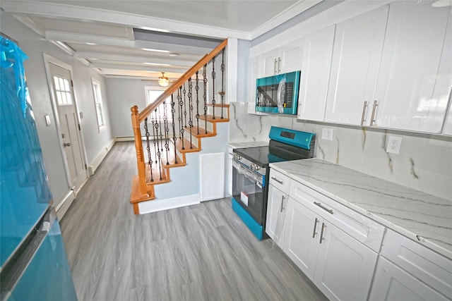 67 Maplewood Dr, Westbury, NY 11590 - kitchen with stainless steel electric range, light wood finished floors, white cabinets, light stone countertops, and ceiling fan