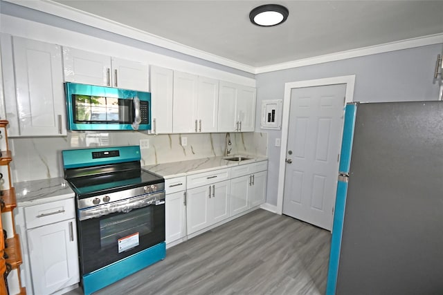 67 Maplewood Dr, Westbury, NY 11590 - kitchen featuring appliances with stainless steel finishes, wood finished floors, white cabinetry, ornamental molding, and light stone countertops