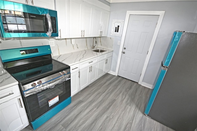 67 Maplewood Dr, Westbury, NY 11590 - kitchen featuring stainless steel appliances, white cabinetry, light wood-type flooring, and light stone counters