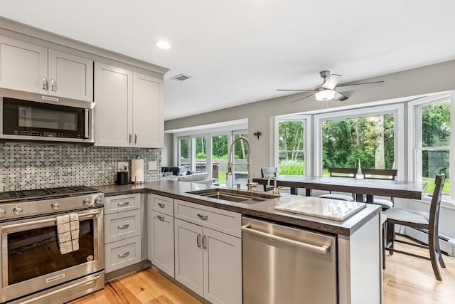 11065 Old Sound Ave, Mattituck, NY 11952 - kitchen with stainless steel appliances, a peninsula, a ceiling fan, light wood-style flooring, and decorative backsplash