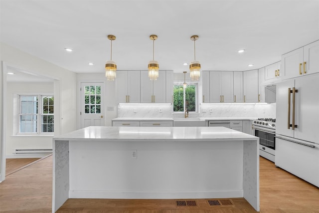 15 Benedict Ave, Eastchester, NY 10709 - kitchen with stainless steel appliances, a kitchen island, decorative backsplash, white cabinets, and a baseboard radiator