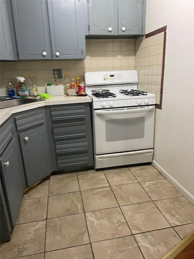 97-10 43rd Ave, Corona, NY 11368 - kitchen with white range with gas cooktop, gray cabinets, decorative backsplash, light countertops, and light tile patterned flooring