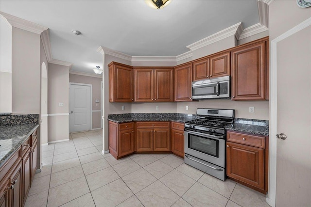 13 Nicole Ct, Copiague, NY 11726 - kitchen with stainless steel appliances, ornamental molding, dark stone countertops, light tile patterned floors, and brown cabinets