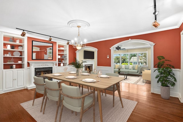 2 Ann Pl, Valhalla, NY 10595 - dining space featuring a warm lit fireplace, track lighting, wainscoting, wood finished floors, and crown molding
