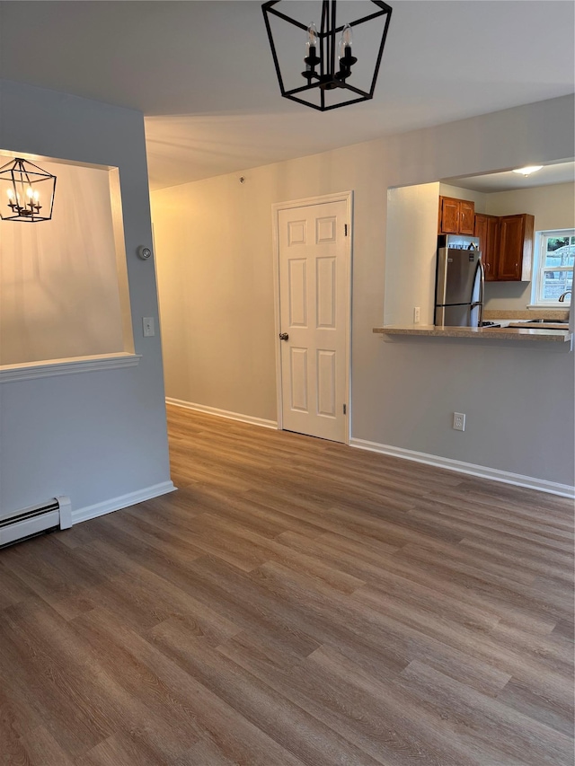 21 Lexington Hl Unit 8, Harriman, NY 10926 - unfurnished living room featuring a chandelier, wood finished floors, and baseboard heating