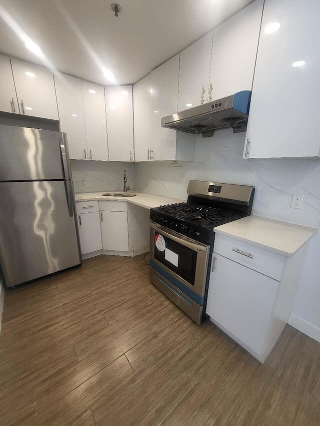4218 147th St Unit 2E, Flushing, NY 11355 - kitchen with appliances with stainless steel finishes, under cabinet range hood, white cabinetry, wood finished floors, and backsplash