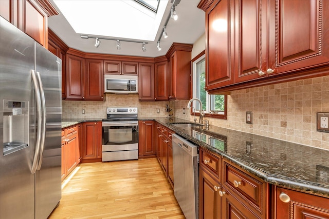 18 Gainsboro Ln, Syosset, NY 11791 - kitchen with appliances with stainless steel finishes, a skylight, light wood-type flooring, and dark stone counters