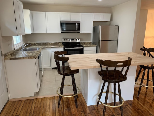 604 Basket Rd, Long Eddy, NY 12760 - kitchen with appliances with stainless steel finishes, wood counters, white cabinets, light wood-style flooring, and a kitchen breakfast bar