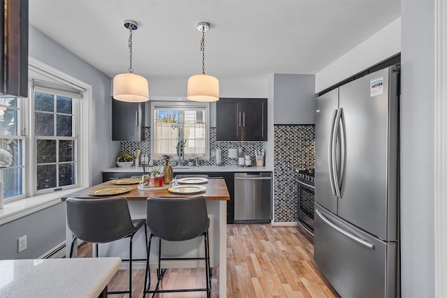 28 Centre St, Yonkers, NY 10701 - kitchen featuring stainless steel appliances, a breakfast bar, tasteful backsplash, and light wood finished floors