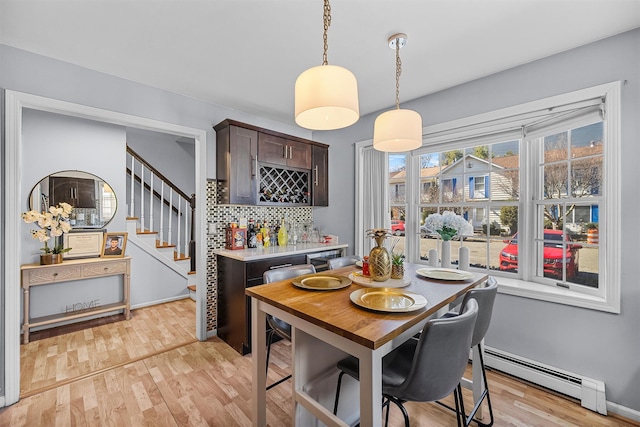 28 Centre St, Yonkers, NY 10701 - dining room with a baseboard heating unit, light wood-style floors, stairway, and bar area