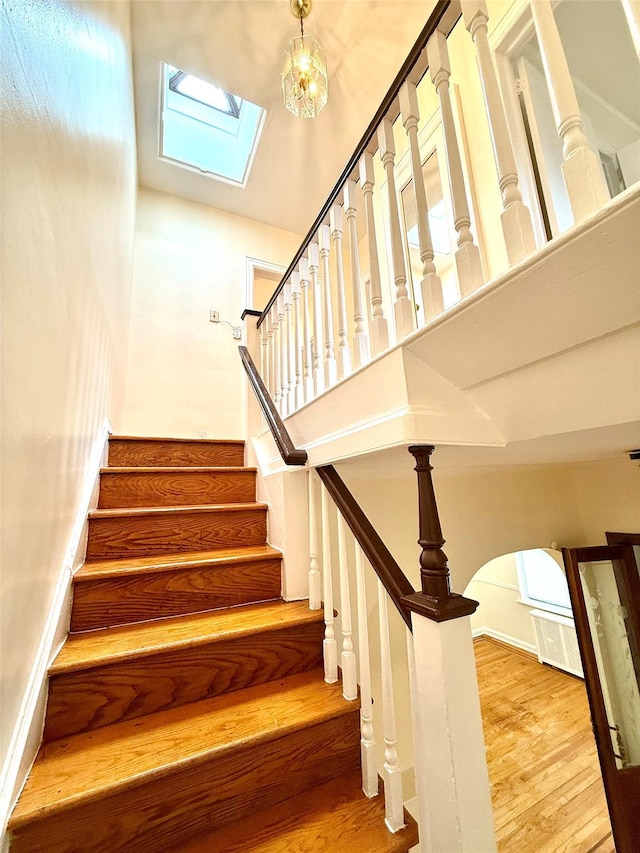 7267 Yellowstone Blvd, Forest Hills, NY 11375 - stairs featuring wood finished floors, arched walkways, a towering ceiling, and a skylight