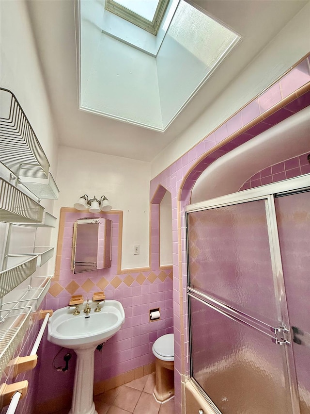 7267 Yellowstone Blvd, Forest Hills, NY 11375 - bathroom with a skylight, tile patterned floors, tile walls, a shower with door, and wainscoting