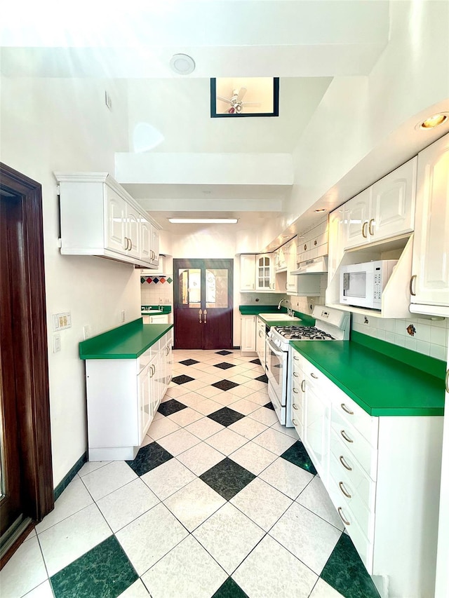 7267 Yellowstone Blvd, Forest Hills, NY 11375 - kitchen with white appliances, white cabinetry, french doors, and under cabinet range hood