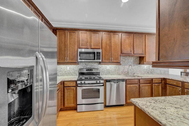 2509 Sylvan Loop, Wappingers Falls, NY 12590 - kitchen with stainless steel appliances, crown molding, light stone countertops, brown cabinets, and light wood-style floors