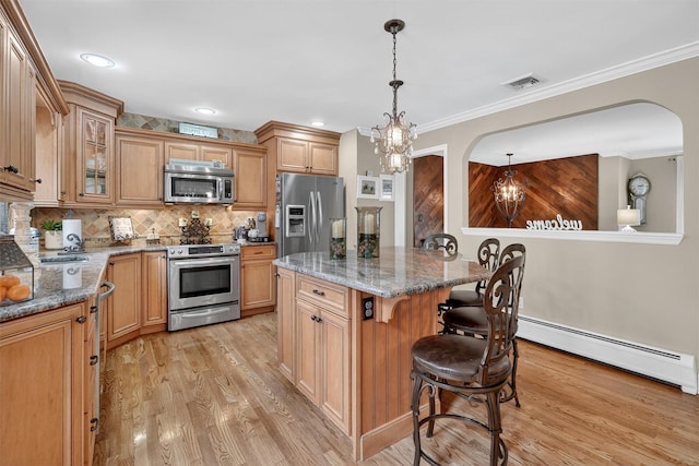 69 Oakland Pl, Nanuet, NY 10954 - kitchen featuring stainless steel appliances, a baseboard radiator, arched walkways, light wood-type flooring, and a kitchen breakfast bar