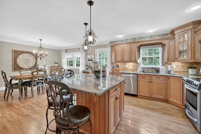 69 Oakland Pl, Nanuet, NY 10954 - kitchen featuring appliances with stainless steel finishes, a chandelier, a breakfast bar, light stone counters, and ornamental molding