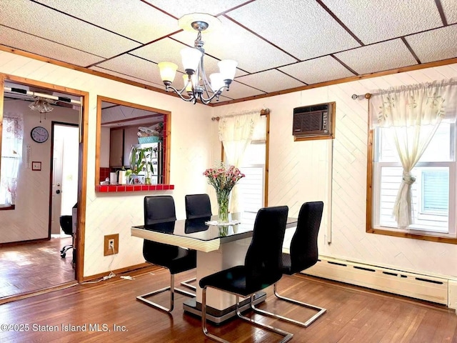 3516 Fillmore Ave, Brooklyn, NY 11234 - dining space featuring baseboard heating, wooden walls, a chandelier, wood finished floors, and a wall mounted AC