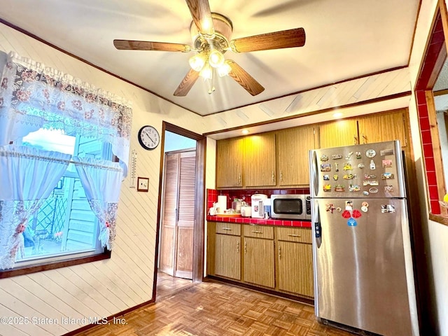3516 Fillmore Ave, Brooklyn, NY 11234 - kitchen featuring stainless steel appliances, tile countertops, a ceiling fan, wood walls, and brown cabinets