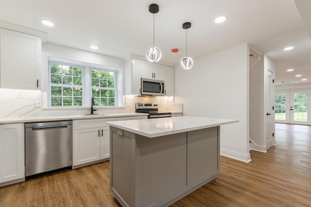 24 Sol Dr, Carmel, NY 10512 - kitchen featuring appliances with stainless steel finishes, light wood-type flooring, tasteful backsplash, a kitchen island, and white cabinetry