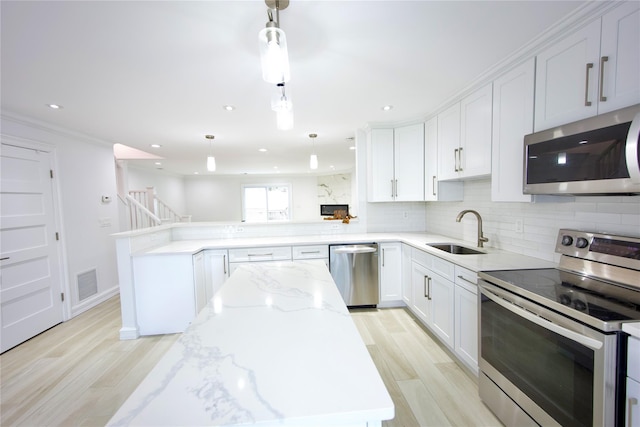 59 Stratford Grn Unit 59, Farmingdale, NY 11735 - kitchen with appliances with stainless steel finishes, a peninsula, decorative backsplash, light wood-type flooring, and light stone countertops
