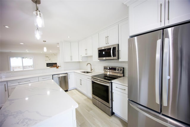 59 Stratford Grn Unit 59, Farmingdale, NY 11735 - kitchen featuring appliances with stainless steel finishes, white cabinetry, backsplash, light wood-type flooring, and light stone counters