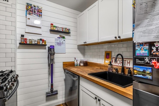 855 E Broadway Unit 4A, Long Beach, NY 11561 - kitchen with butcher block countertops, appliances with stainless steel finishes, white cabinets, decorative backsplash, and wooden walls