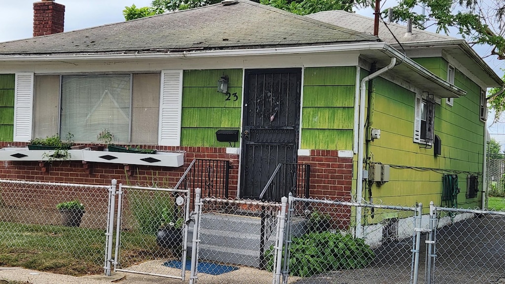 23 Peters Ave, Hempstead, NY 11550 - view of front of home featuring a gate, a shingled roof, a fenced front yard, and a chimney
