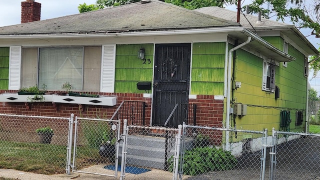 23 Peters Ave, Hempstead, NY 11550 - view of front of home featuring a gate, a shingled roof, a fenced front yard, and a chimney