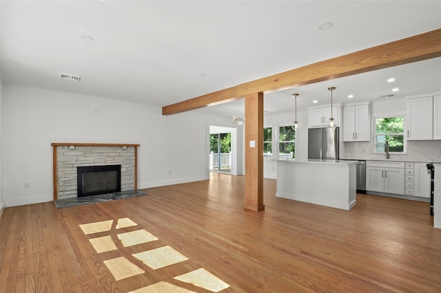 41 Forest Ave, Cortlandt Manor, NY 10567 - unfurnished living room featuring light wood-style floors, recessed lighting, a stone fireplace, and beamed ceiling