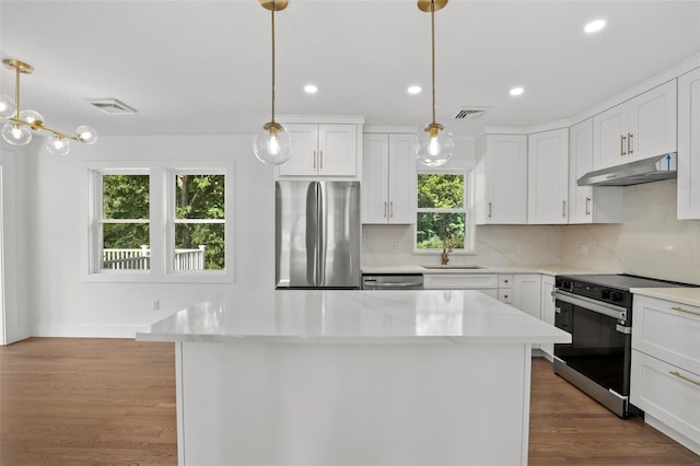 41 Forest Ave, Cortlandt Manor, NY 10567 - kitchen with appliances with stainless steel finishes, under cabinet range hood, a kitchen island, backsplash, and white cabinetry