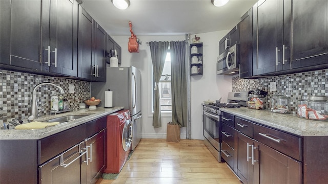 450 W 152nd St Unit 52, New York Manhattan, NY 10031 - kitchen featuring appliances with stainless steel finishes, light wood-type flooring, tasteful backsplash, washer / clothes dryer, and light stone countertops
