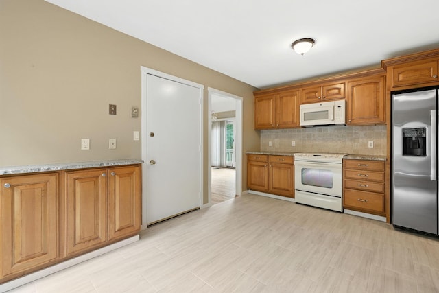 206 Heritage Unit A, Somers, NY 10589 - kitchen with white appliances, brown cabinetry, backsplash, and light stone countertops