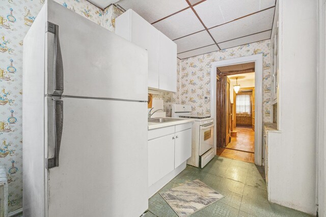 2117 38th St, Astoria, NY 11105 - kitchen with white appliances, wallpapered walls, light countertops, white cabinets, and light floors