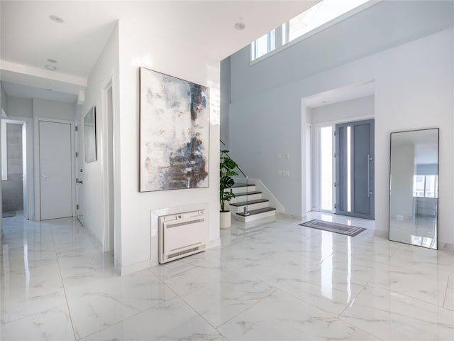 85 Erie Ave, Atlantic Beach, NY 11509 - hallway featuring light marble finish flooring, heating unit, stairs, and a towering ceiling