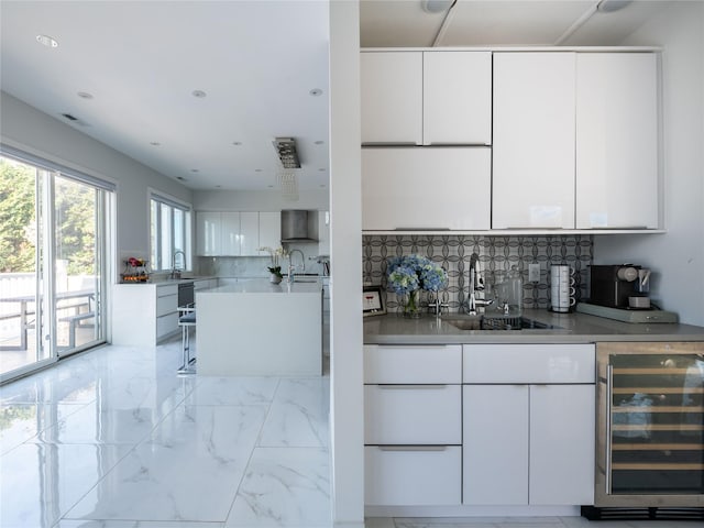85 Erie Ave, Atlantic Beach, NY 11509 - kitchen with beverage cooler, modern cabinets, light marble finish floors, and white cabinetry