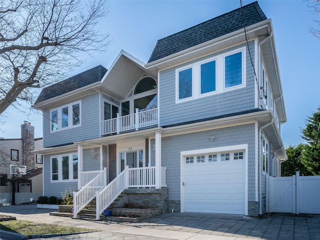 85 Erie Ave, Atlantic Beach, NY 11509 - traditional-style house with a balcony, a garage, roof with shingles, a gate, and driveway