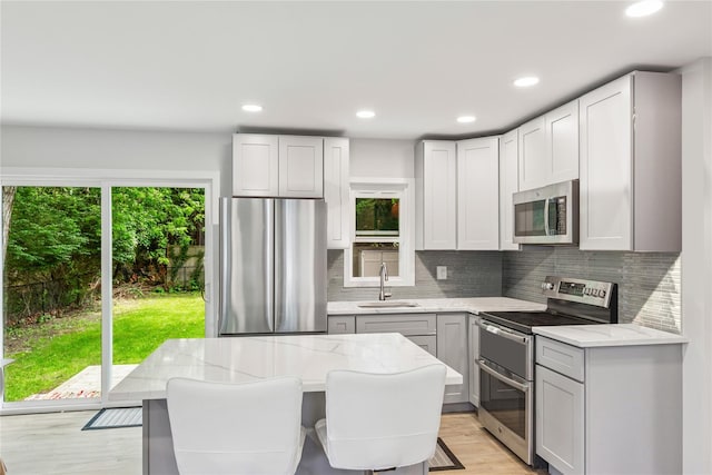 5 Coolidge Rd, Hampton Bays, NY 11946 - kitchen featuring stainless steel appliances, light wood-style flooring, backsplash, light stone counters, and recessed lighting