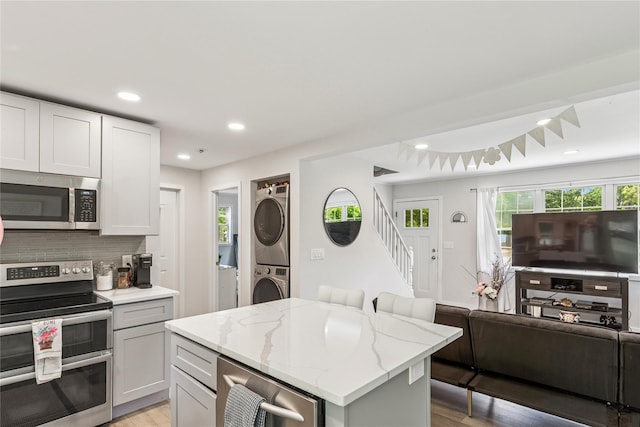 5 Coolidge Rd, Hampton Bays, NY 11946 - kitchen with appliances with stainless steel finishes, estacked washer and dryer, light wood-type flooring, light stone countertops, and open floor plan