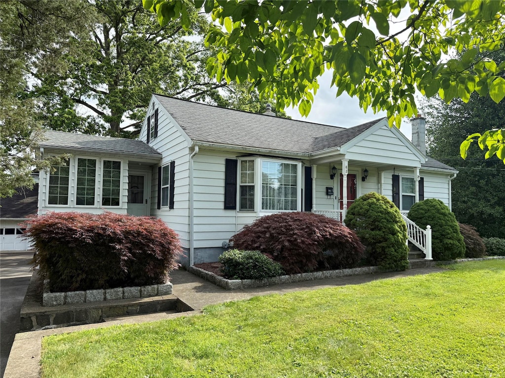 63 Washburns Ln, Stony Point, NY 10980 - view of front facade featuring a chimney, a front yard, a garage, roof with shingles, and concrete driveway