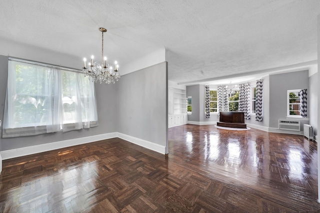 6851 Clyde St, Forest Hills, NY 11375 - empty room featuring a chandelier, radiator heating unit, plenty of natural light, a wall mounted air conditioner, and a textured ceiling