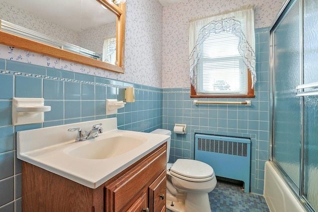 12 Malone Ave, Garnerville, NY 10923 - bathroom featuring radiator, wallpapered walls, vanity, a wainscoted wall, and shower / bath combination with glass door