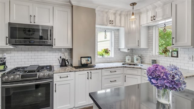 16 Clement St, Glen Cove, NY 11542 - kitchen with appliances with stainless steel finishes, tasteful backsplash, white cabinetry, ornamental molding, and healthy amount of natural light