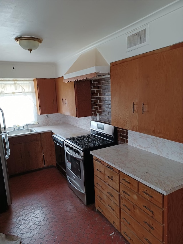 118 Allen St, Hempstead, NY 11550 - kitchen featuring stainless steel gas range oven, freestanding refrigerator, light countertops, and brown cabinetry