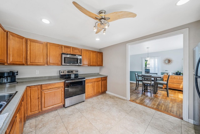 4 Jones St N, Patchogue, NY 11772 - kitchen featuring stainless steel appliances, ceiling fan, brown cabinetry, light tile patterned flooring, and recessed lighting