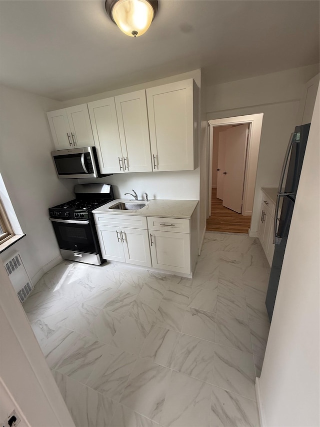 67-25 Clyde St Unit 5D, Forest Hills, NY 11375 - kitchen featuring stainless steel microwave, black gas stove, light marble finish floors, and white cabinetry