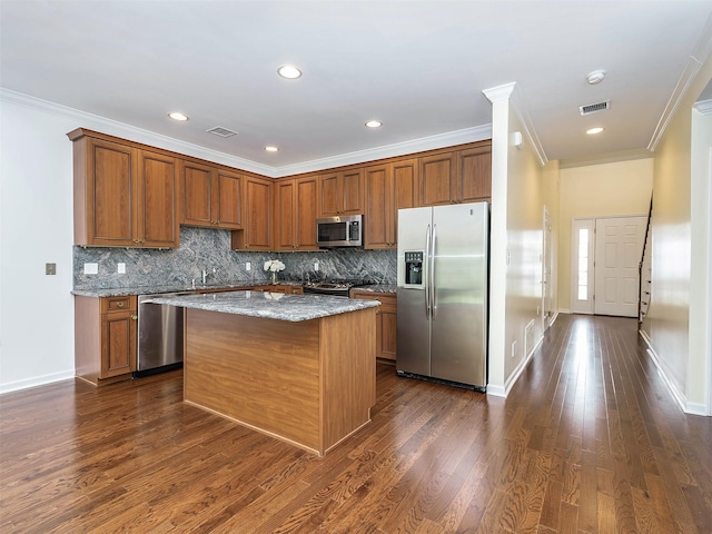 195 Pond View Dr Unit Ca0208, Port Washington, NY 11050 - kitchen featuring stainless steel appliances, light stone counters, crown molding, a center island, and brown cabinets