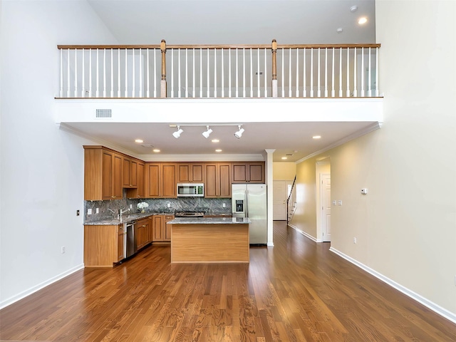 195 Pond View Dr Unit Ca0208, Port Washington, NY 11050 - kitchen featuring stainless steel appliances, decorative backsplash, a kitchen island, dark wood finished floors, and crown molding